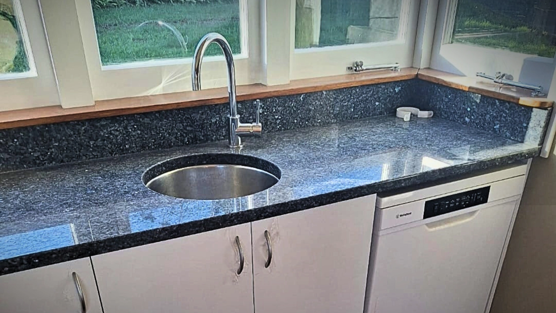 Plumber connecting dishwasher water supply and waste under a Napier bench